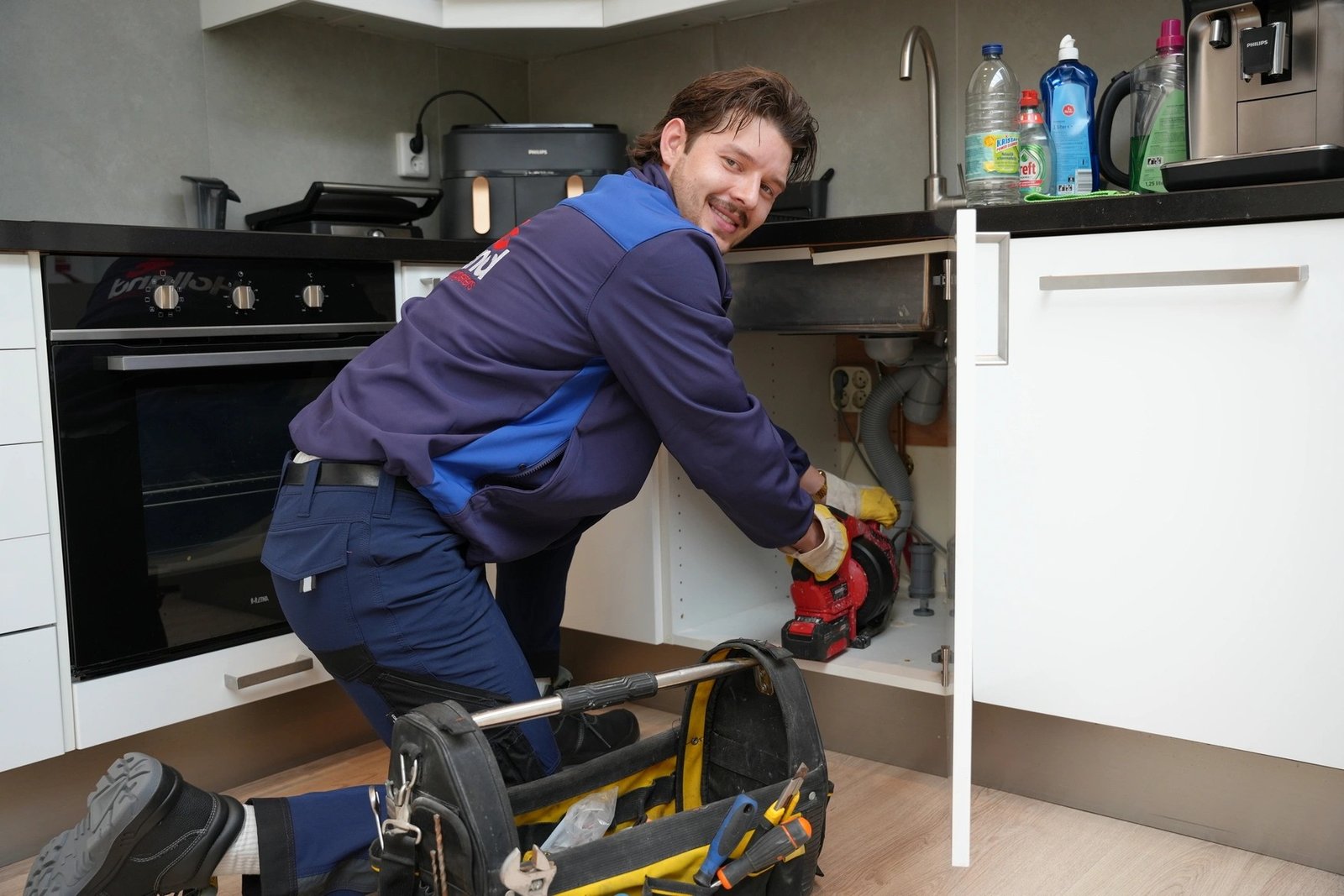 Loodgieter van Holland Loodgieters aan het werk in een keuken in Den Haag met professionele gereedschapstas